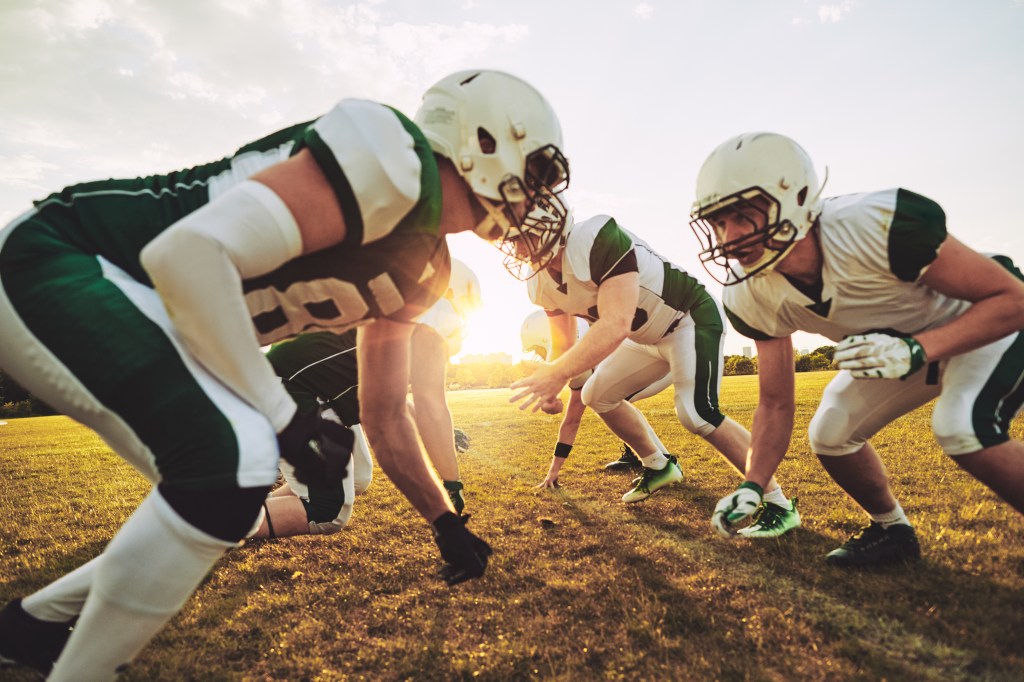 Team of young American football players lining up in formation during an afternoon practice session